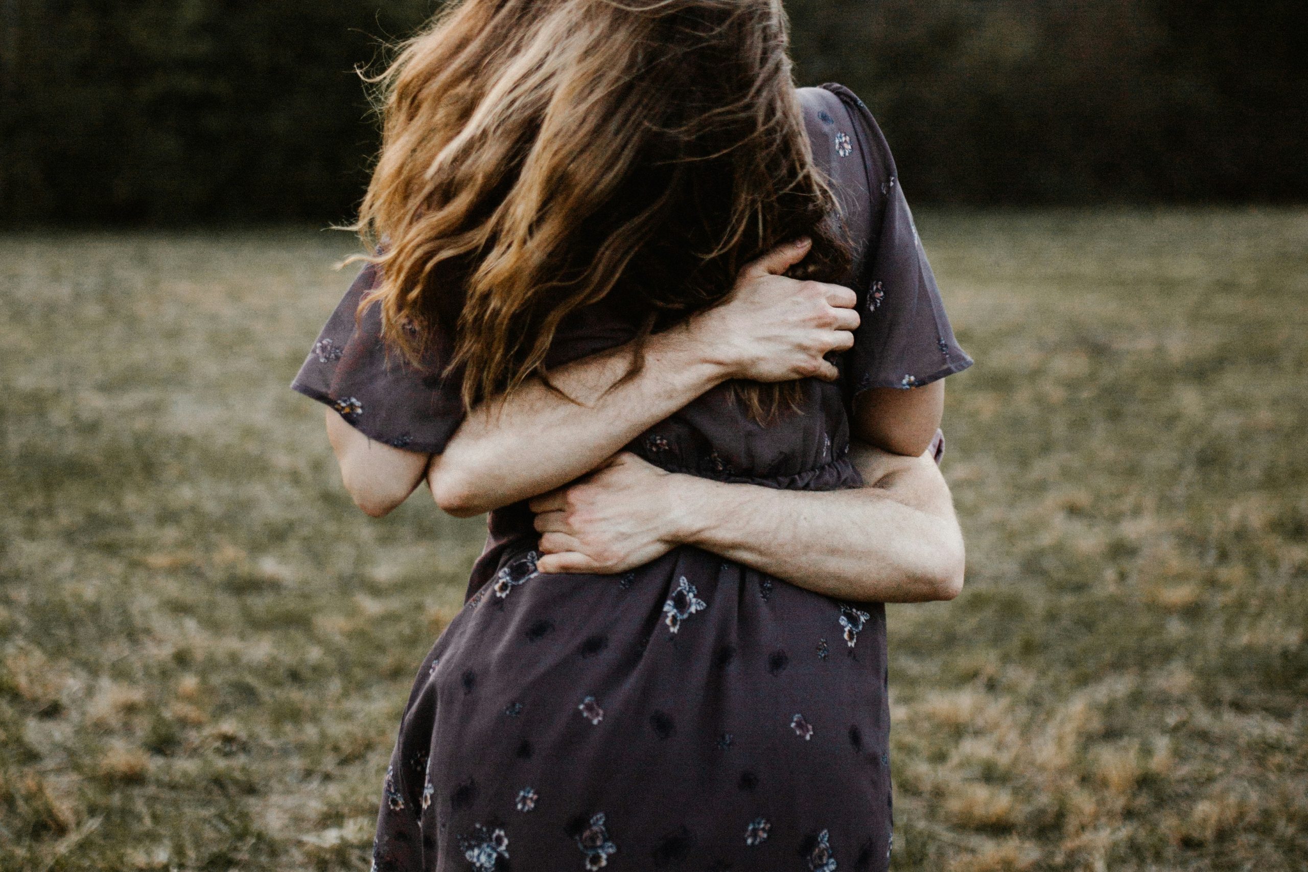 Back view of girl being hugged, with arms wrapped around her